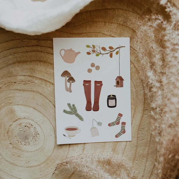 Ansichtkaart van Tilda & Theo met gezellig herfst tafereel als regenlaarzen, theepot, warme sokken en koekjes gedrukt op hoogwaardig, natuurlijk crème papier