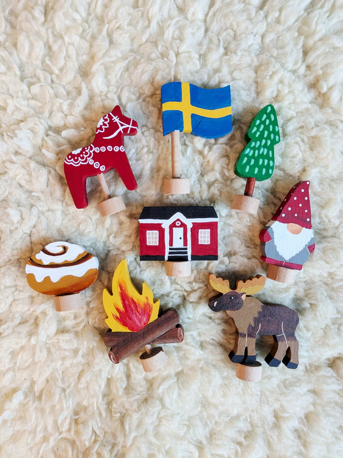 Acht Zweedse houten stekers van Vossebos voor de jaarring met Dalarna-paardje, Zweedse vlag, dennenboom, rood huisje, tomte, kampvuur, eland en kanelbulle